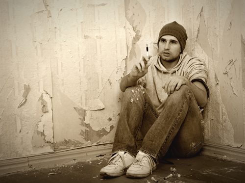 Top 5 Myths About Addiction - man sitting in corner with needle