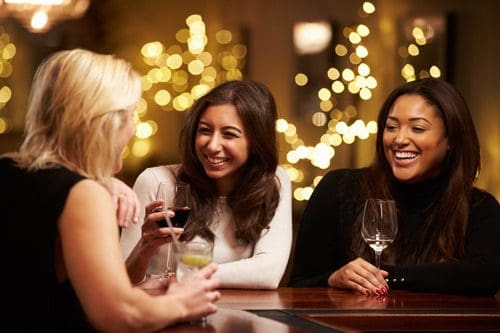 3 women having drinks at bar