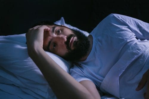 man wide awake at night in bed