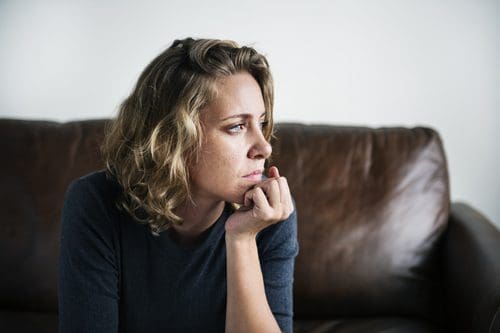 woman sitting on couch thinking