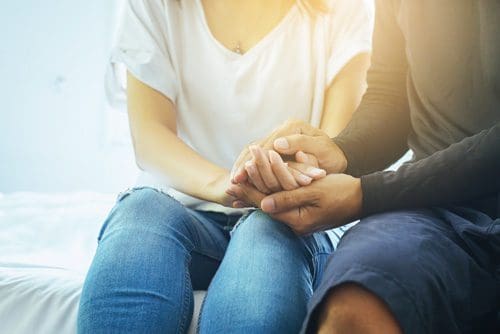 two people sitting close with hands on top of each other