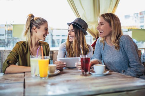 three young women friends drinking mocktails at a cafe