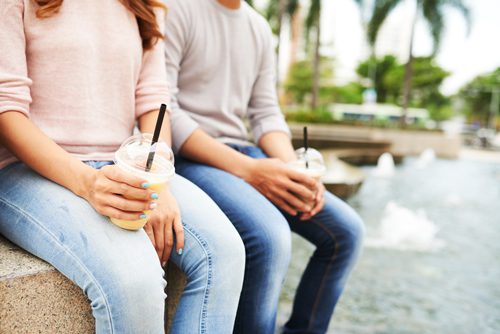 woman and man on date, sitting near fountain drinking iced coffee - dating