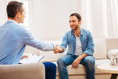 man in therapist's office shaking hand with his male therapist - outpatient treatment