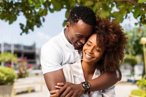 beautiful happy African American couple embracing outdoors - romance