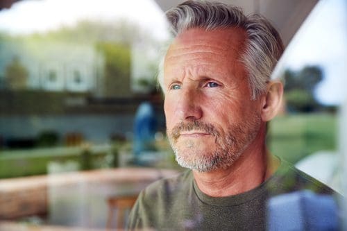 older man looking out window - treatment - COVID-19