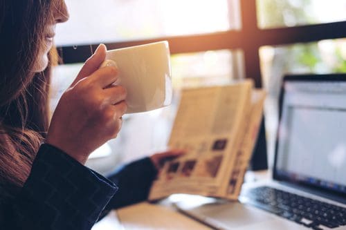 woman drinking coffee and reading newspaper - routine