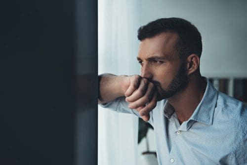 handsome man in deep thought looking out window - back to rehab