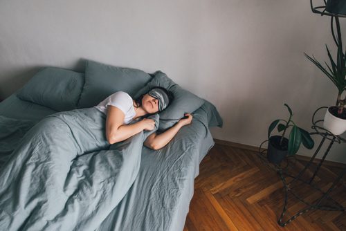 woman sleeping on bed with eye mask on - sleep habits
