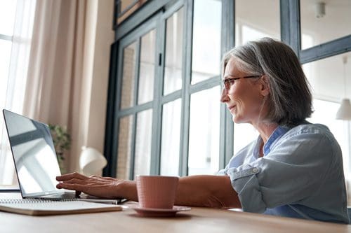 pretty senior woman doing research on laptop at home - rehab