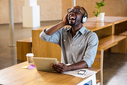 handsome black man using laptop and headphones is laughing
