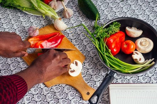 hands of Black man cutting up fresh vegetables - whole foods