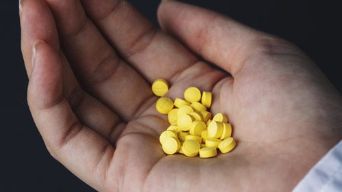 hand holding twenty or so small yellow pills - clonazepam withdrawal