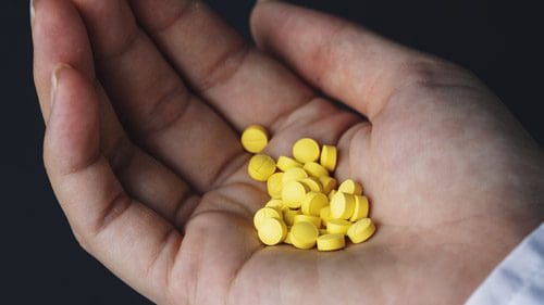 hand holding twenty or so small yellow pills - clonazepam withdrawal