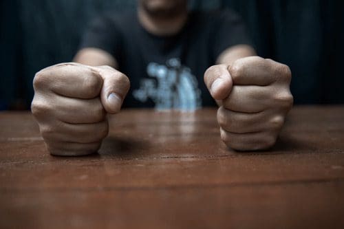 cropped shot of fisted hands on a table - anger management