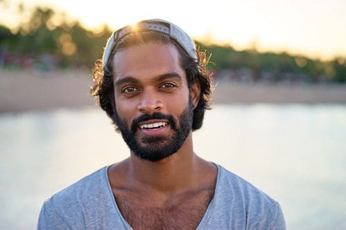 very handsome smiling Black young man outdoors in baseball cap turned backwards - burnout