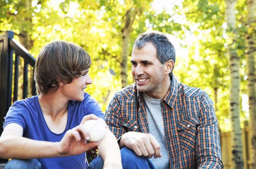 man and his teenage son smiling and talking outdoors - child drugs and alcohol