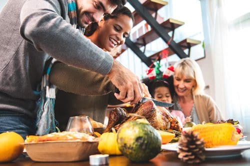 lovely couple carving turkey together while their daughter sits on grandma's lap - Thanksgiving and recovery