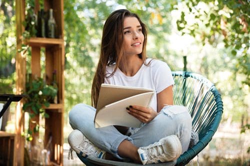 pretty Latina woman sitting outside writing in a spiral notebook - setting goals