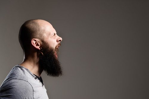side profile of bearded man with shaved head yelling - anger
