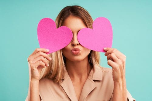 woman holding pink cutout hearts up to her face - Valentine's Day