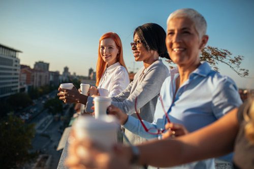 diverse group of women drinking coffee and talking on a rooftop - recovery