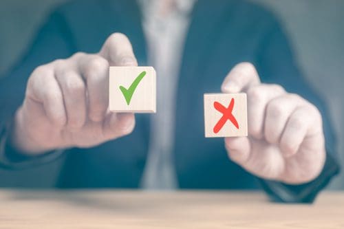 cropped shot of mans hands holding wooden blocks; one has a green check mark and the other has a red x - outpatient treatment program