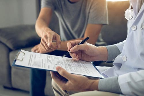 cropped shot of man giving doctor details while doctor fills out form - alcohol withdrawal