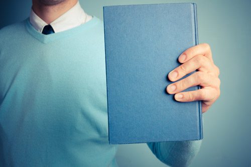 cropped shot of a man holding up a hardback blue book - twelve-step programs