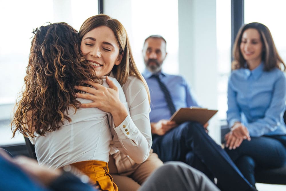 family members hugging during addiction treatment group session