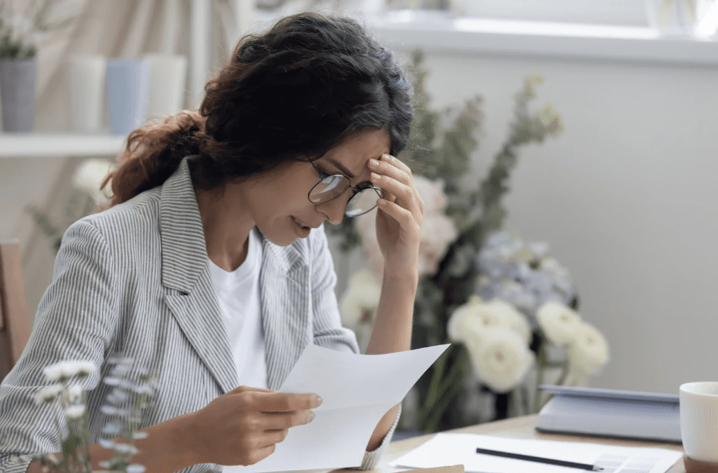 A woman looking stressed while doing paperwork.