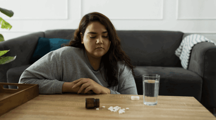 A woman sitting in front of pills.