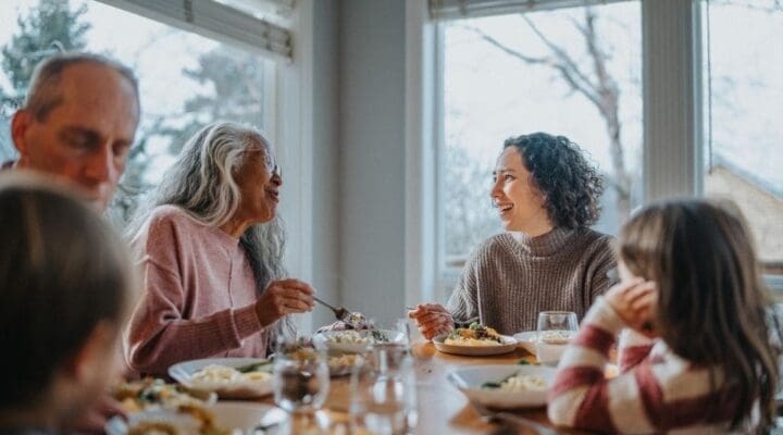 A multigenerational family enjoying a holiday meal together, sharing laughter and conversation around a dining table filled with food.